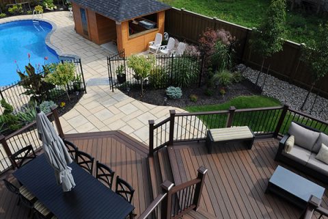 Image of a finished backyard with a Trex Spiced Rum deck and Cedar cabana accented with a stone patio and a pool