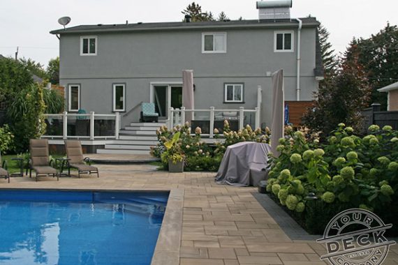 backyard landscape with a stone patio, pool and a low maintenance fiberon deck